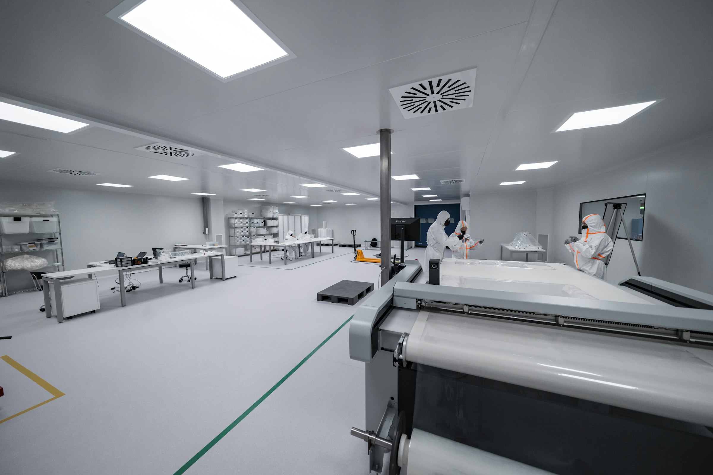 Modern sterile pharmaceutical cleanroom with workers in PPE